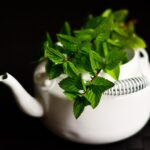 Tazza di tè di menta fumante su un tavolo, ingrediente chiave per migliorare la digestione.