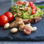 Fette biscottate integrali guarnite con avocado e semi, ideale per una colazione sana e nutriente.