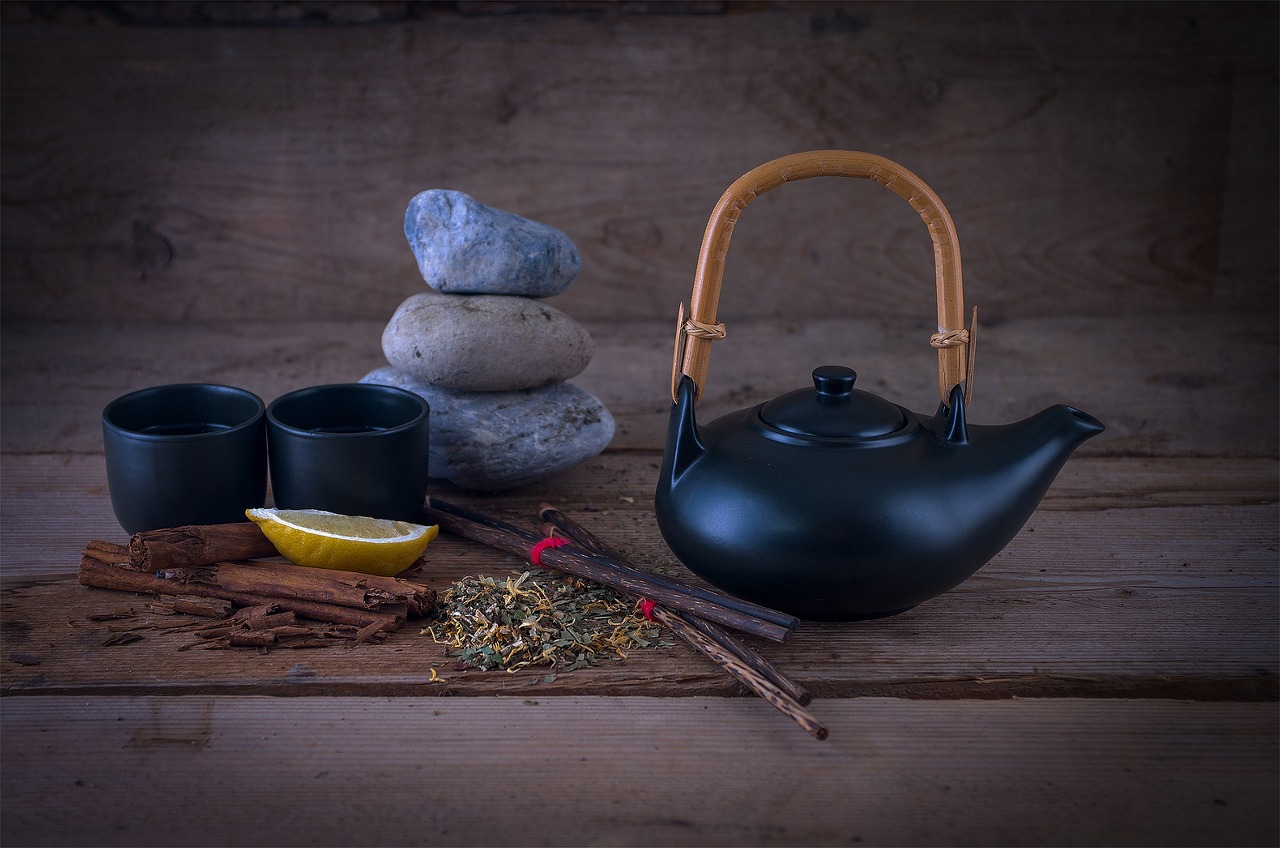 Tazza di tè fumante con foglie di tè e spezie, simbolo di infusi orientali per la digestione.