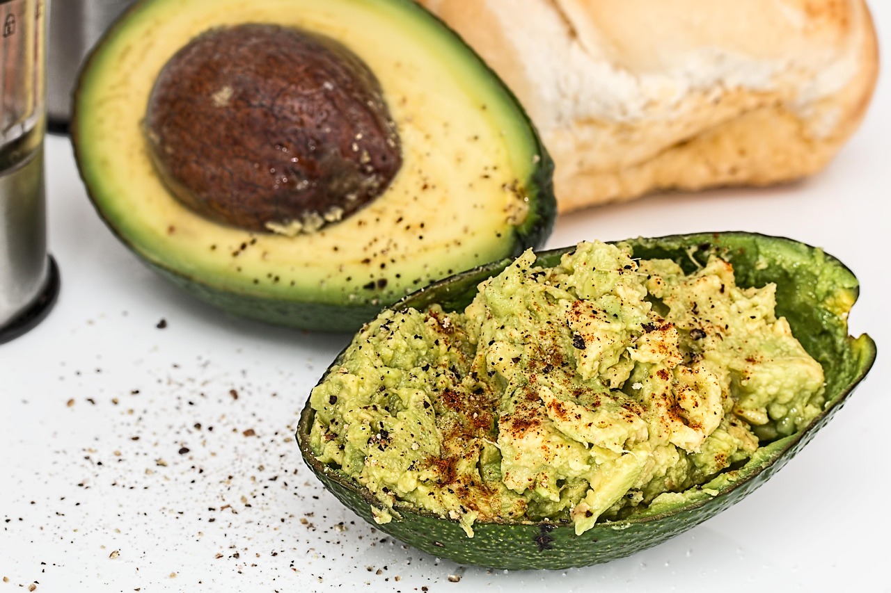 Avocado a fette su un piatto, con ingredienti freschi per abbassare il colesterolo.