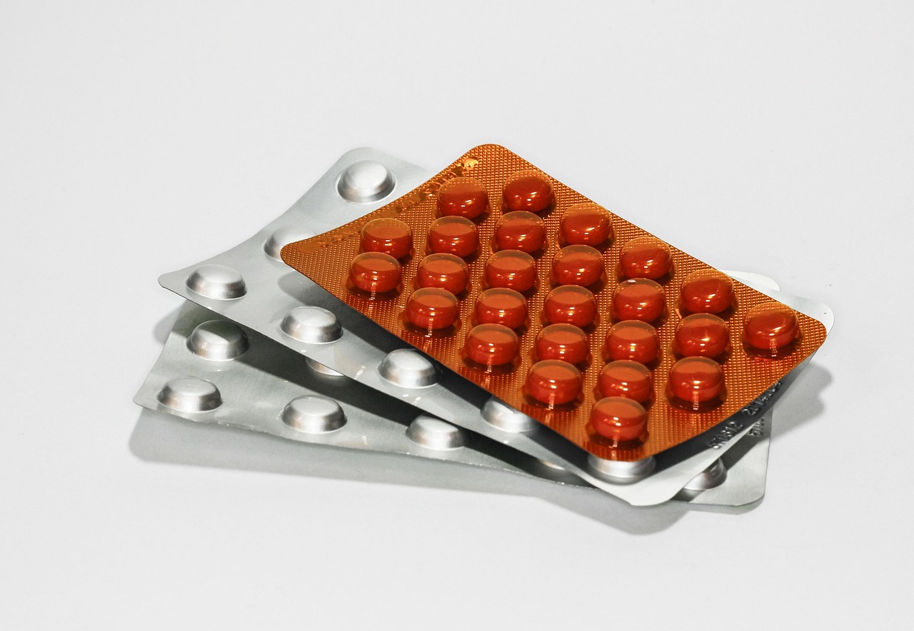 Un flacone di ibuprofene su un tavolo, con pillole sparse e un quaderno di appunti sulla nutrizione.