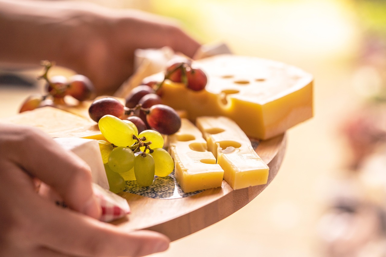 Porzione di formaggio su un tagliere con frutta e noci, rappresentativa di una dieta equilibrata.