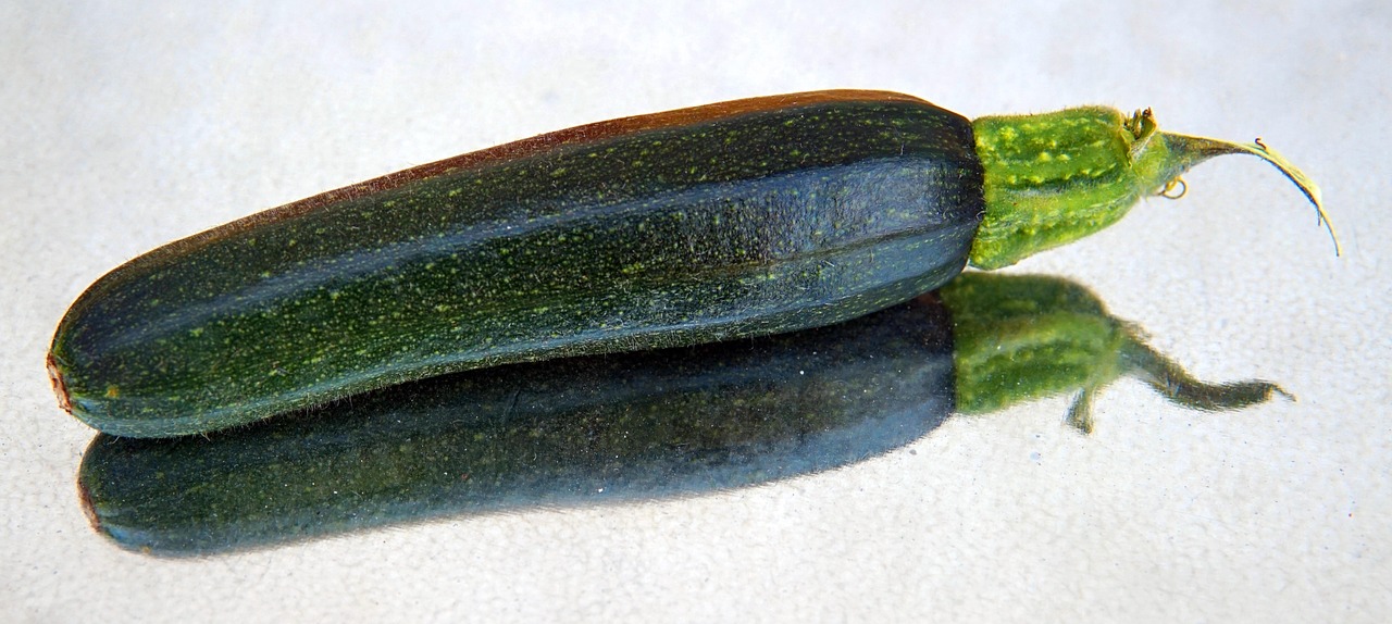 Zucchine verdi fresche su un tavolo, simbolo di salute, ma con segni di scarsa produzione.